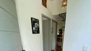 Un pasillo con un mosaico de toros, un cuadro en la pared y una lámpara.