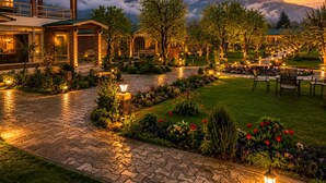 A hotel with a paved walkway, outdoor seating, and a mountain backdrop. - The Orchard Retreat & Spa, Srinagar (Srinagar)