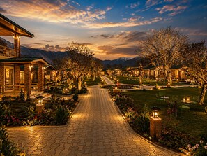 A pathway leading to a row of houses with a mountain backdrop. - The Orchard Retreat & Spa, Srinagar (Srinagar)