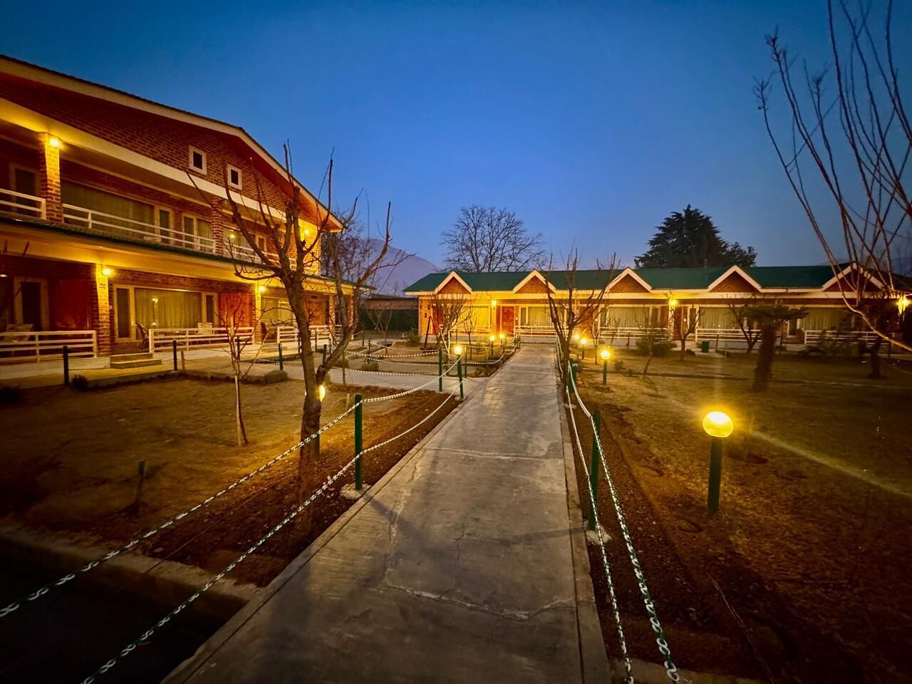 A hotel with multiple buildings, a central pathway, and a fenced area with trees.