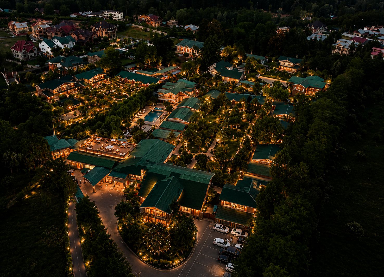 An aerial view of a resort with multiple buildings, a swimming pool, and a parking area.