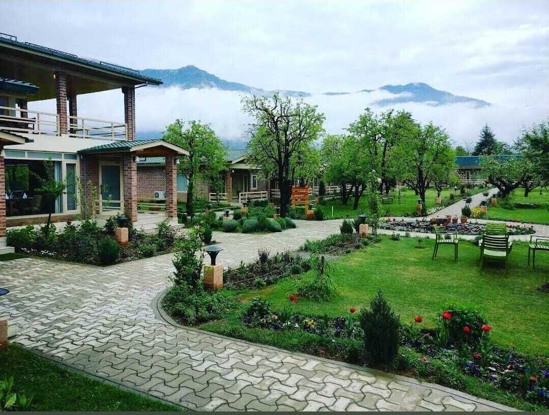 A hotel with a paved courtyard, outdoor seating, and a view of mountains.