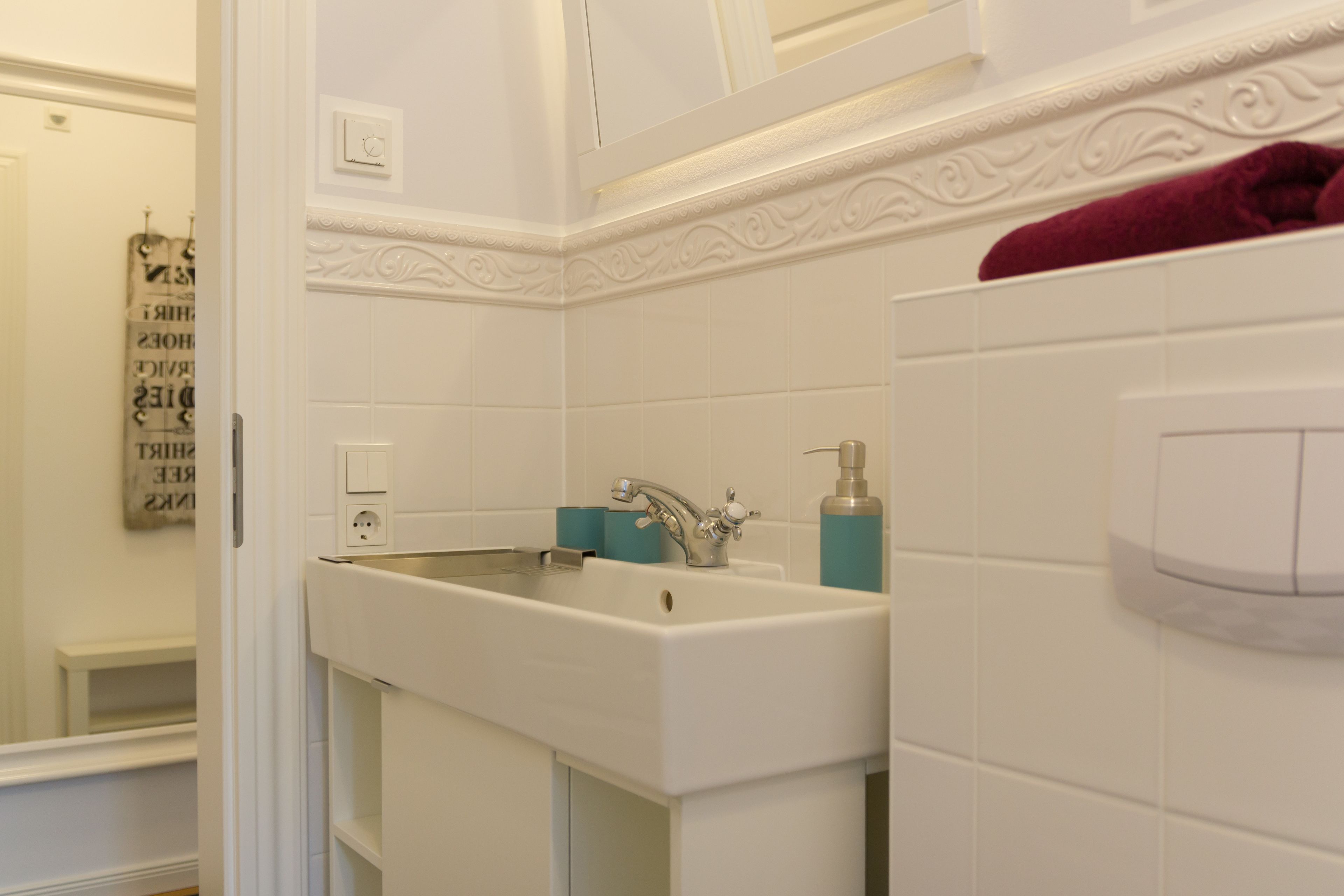 A bathroom with a white sink, a mirror, and a towel rack.