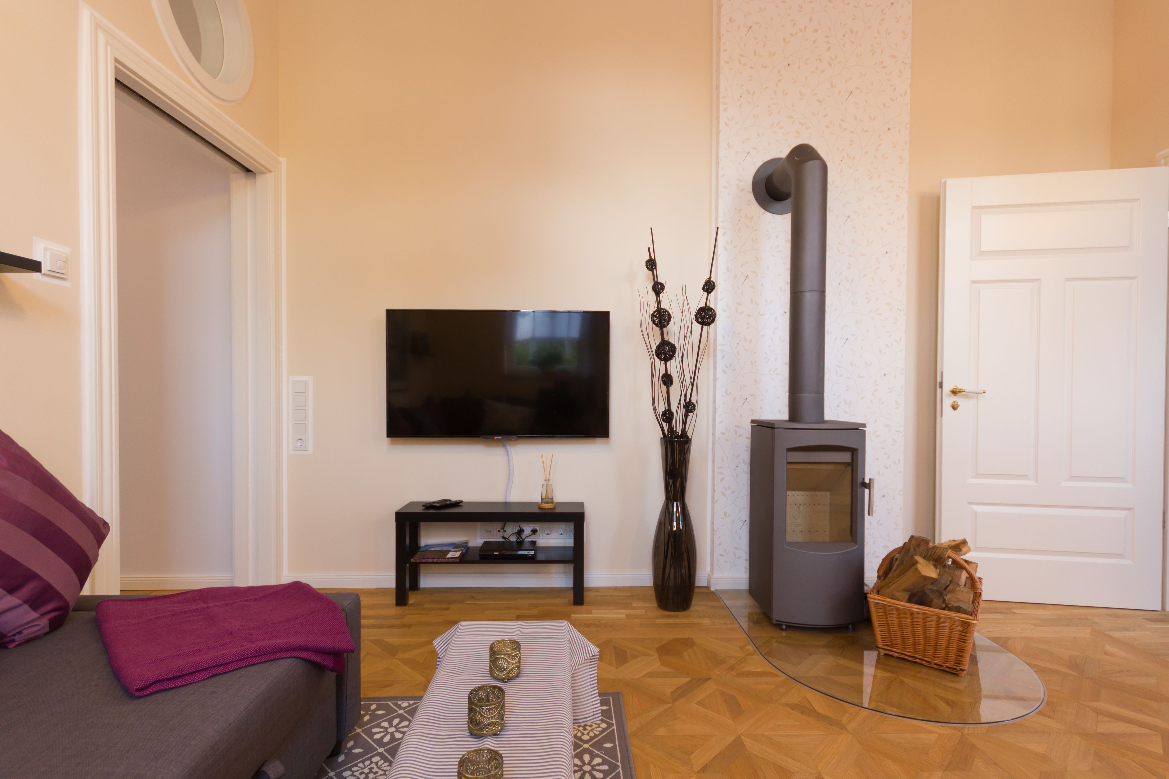 A living room with a sofa, a flat-screen TV, a fireplace, and a decorative vase.