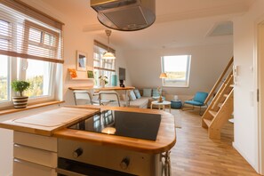 A modern kitchen with a built-in stove, wooden countertops, and a window with blinds. - Villa Ruth (Reichshof)