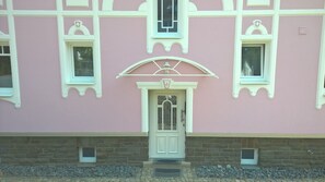 A pink building with a white door and windows, stone foundation, and decorative elements. - Villa Ruth (Reichshof)