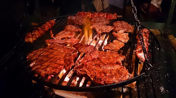 A grill with various meats being cooked. - Hotel Restaurant Margaretenhof (Ueberherrn)