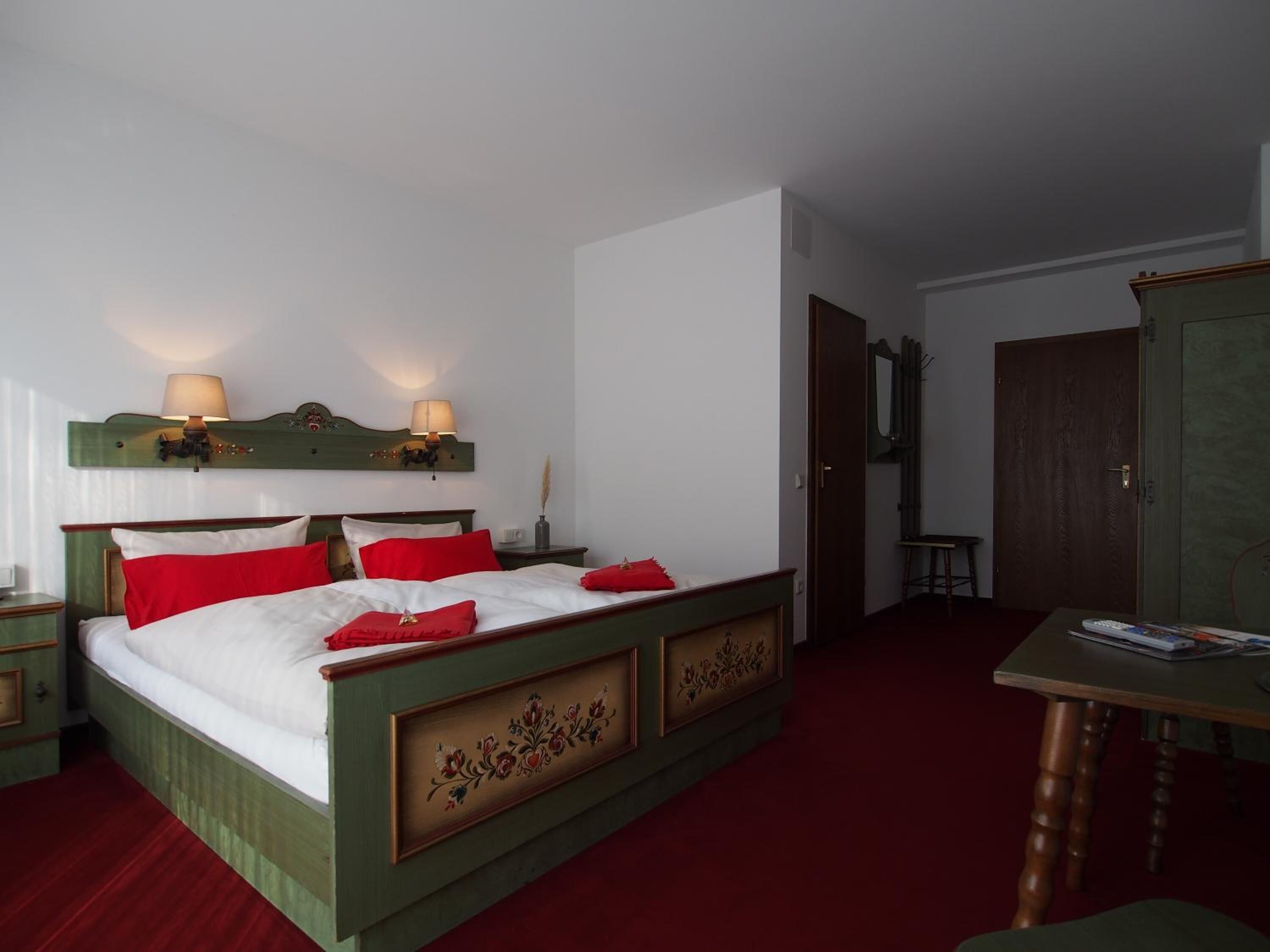 Ett hotellrum med en stor säng, två sänglampor, en träpanel vid sänggaveln, ett litet bord och en garderob.