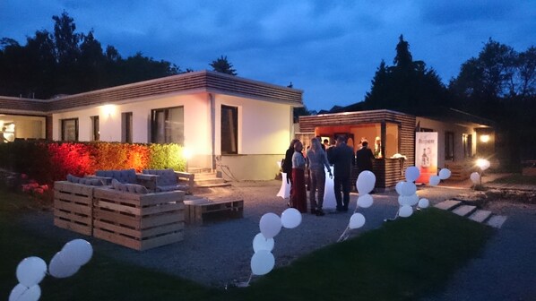 A building with a patio area, outdoor seating, and a small structure with balloons.