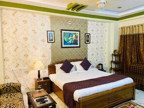 A hotel room with a bed, bedside table, lamp, and a decorative wall.