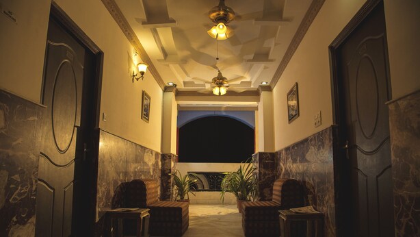 A lobby with marble walls, two doors, a ceiling fan, and two potted plants. - Hotel Meenakshi Udaipur (Udaipur)
