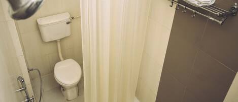 A bathroom with a toilet, shower, and a towel rack with folded towels.