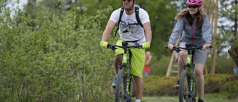 Two people riding bicycles on a path surrounded by greenery.
