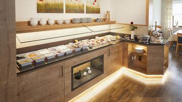 A buffet setup with various food items, a glass display case, and a wooden counter.