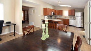 A spacious kitchen with modern appliances, a dining area with a dark wooden table, and a view of the living area.