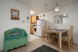 A kitchen with wooden cabinets, a white refrigerator, and a dining table with chairs.