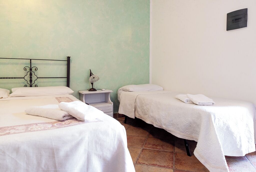 A hotel room with two beds, a nightstand, and a wall clock.