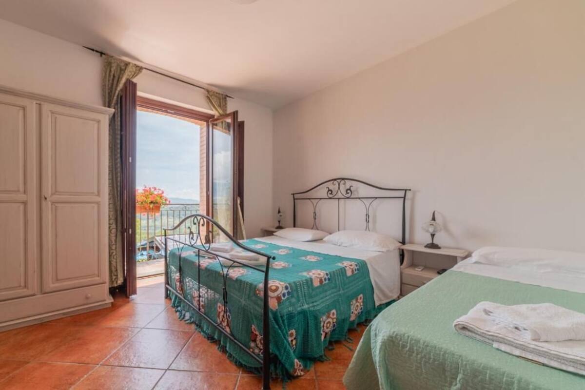 Un dormitorio con cama, mesita de noche, armario y balcón con vistas.