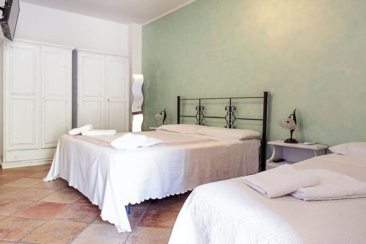 Un dormitorio con dos camas, un armario y una mesita de noche con lámpara.