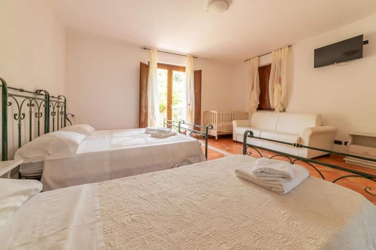 Una habitación con dos camas, un sofá blanco y una televisión en la pared.