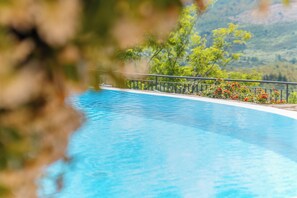 Vista despejada de una piscina con barandilla metálica y montañas al fondo.