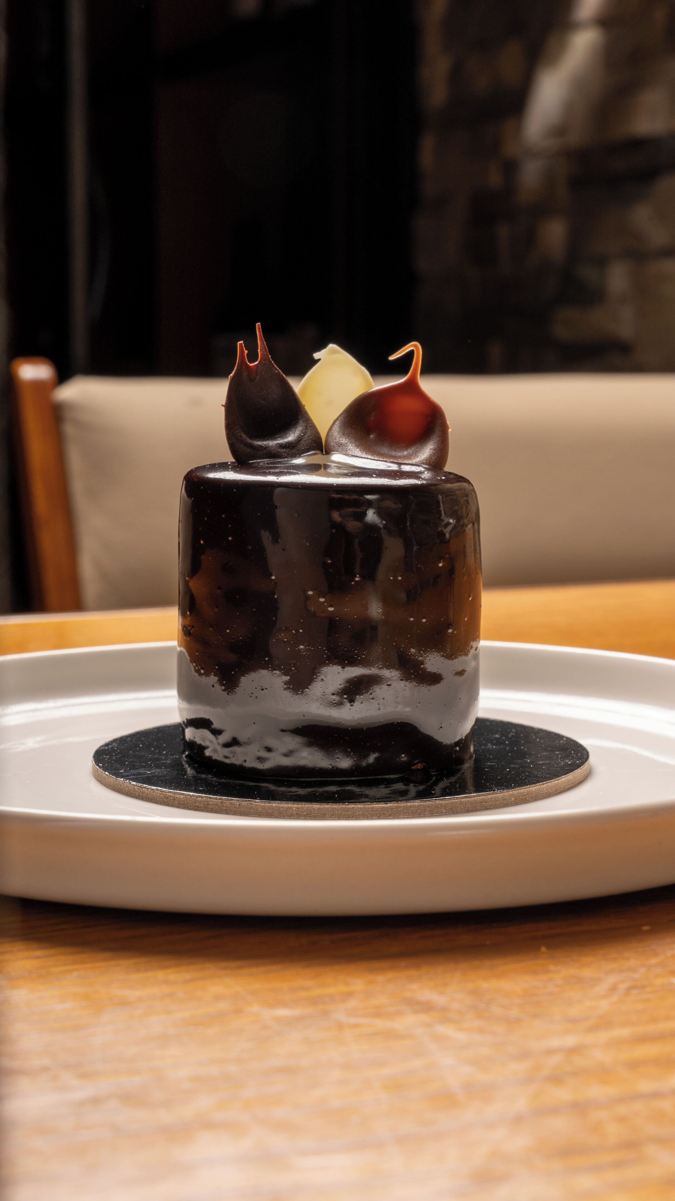 A dessert on a plate with a dark liquid, a white cube, and two chocolate pieces on top.