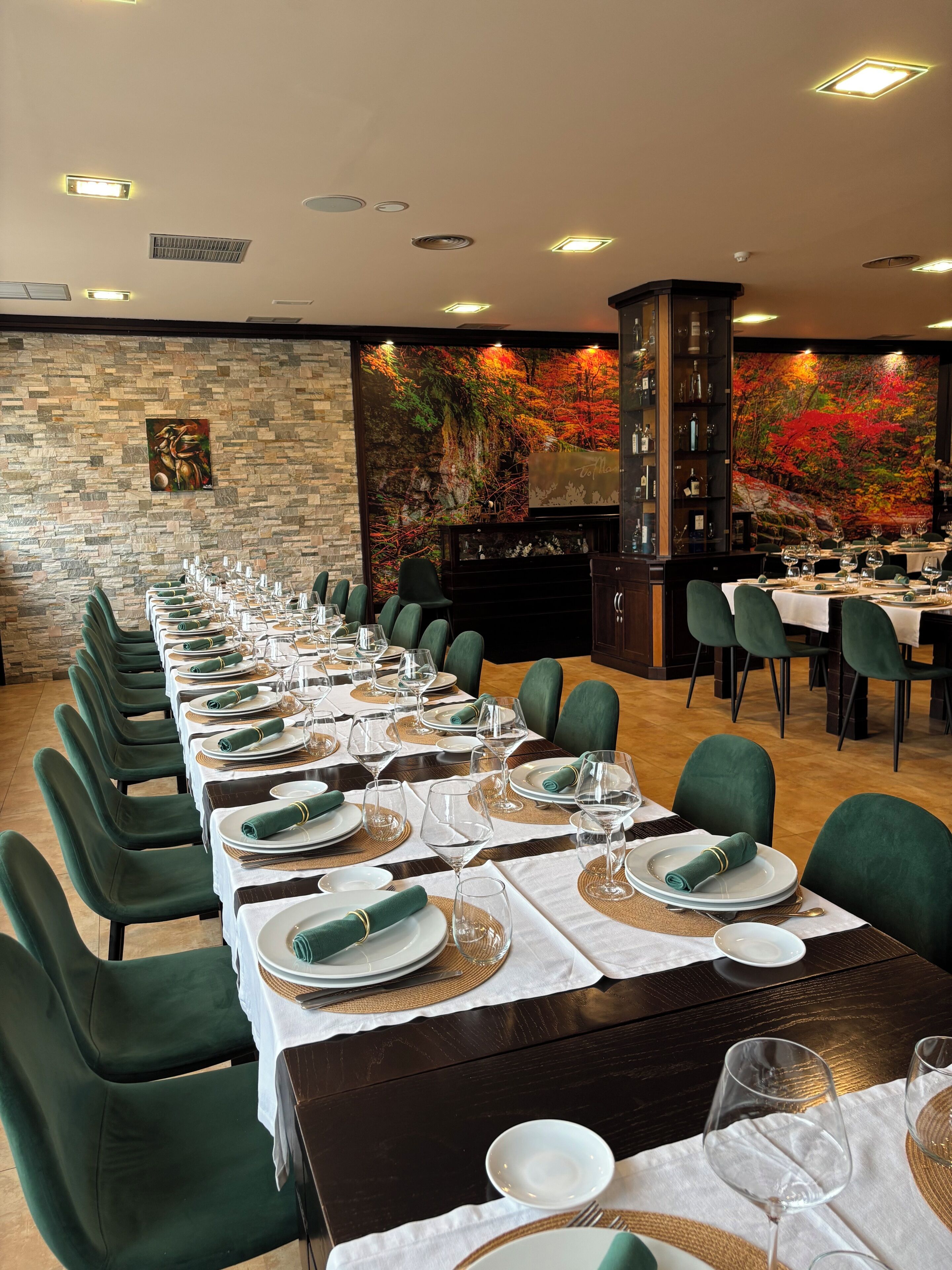 A long dining table set with green chairs, white tablecloths, and gold accents.