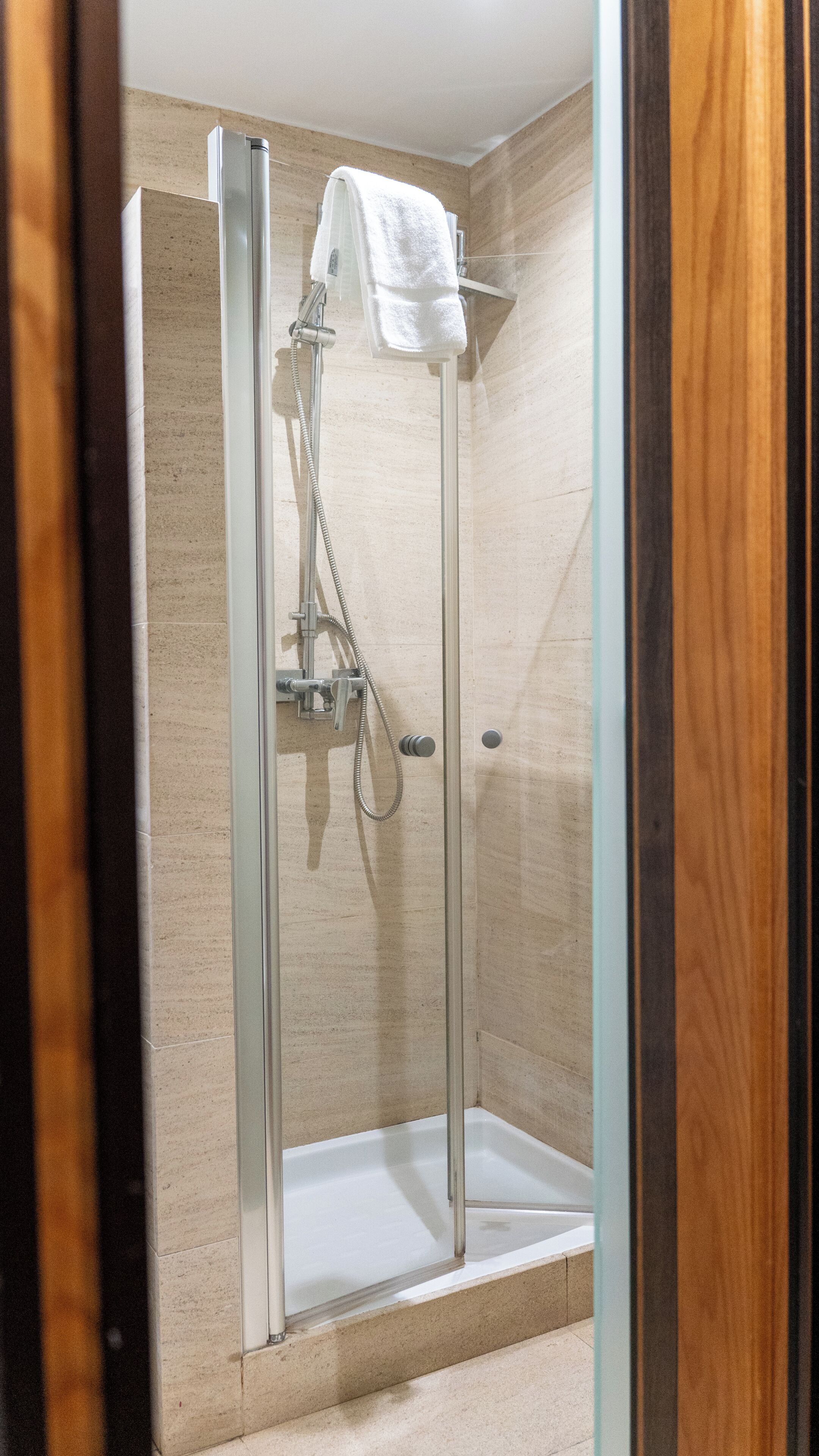 A glass-enclosed shower stall with a white towel on the wall.