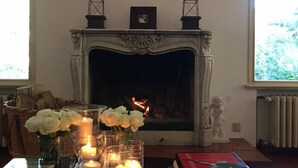 Una chimenea con un cuadro enmarcado encima, un fachaleta con una fotografía pequeña enmarcada, y una estatua a la derecha.