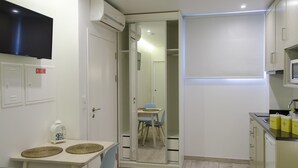 A compact kitchen with a dining area, a television, and a microwave.