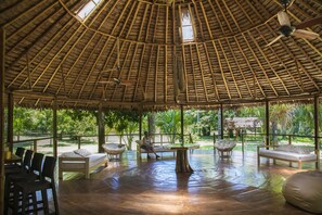 A spacious, open-roofed lounge with wooden furniture and a view of lush greenery. - Amak Iquitos Ecolodge (Indiana)