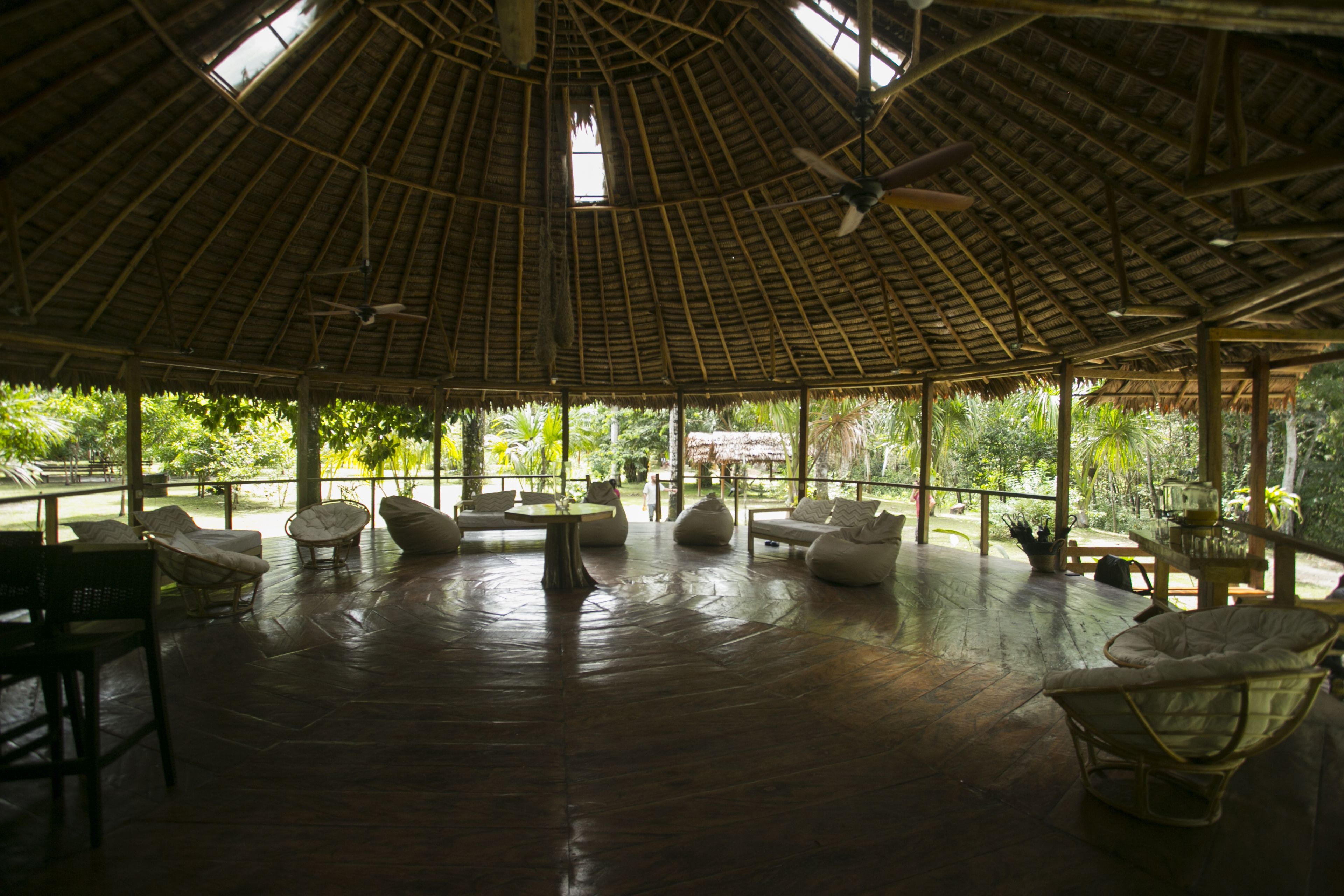An open-air pavilion with a thatched roof, wooden flooring, and seating areas.