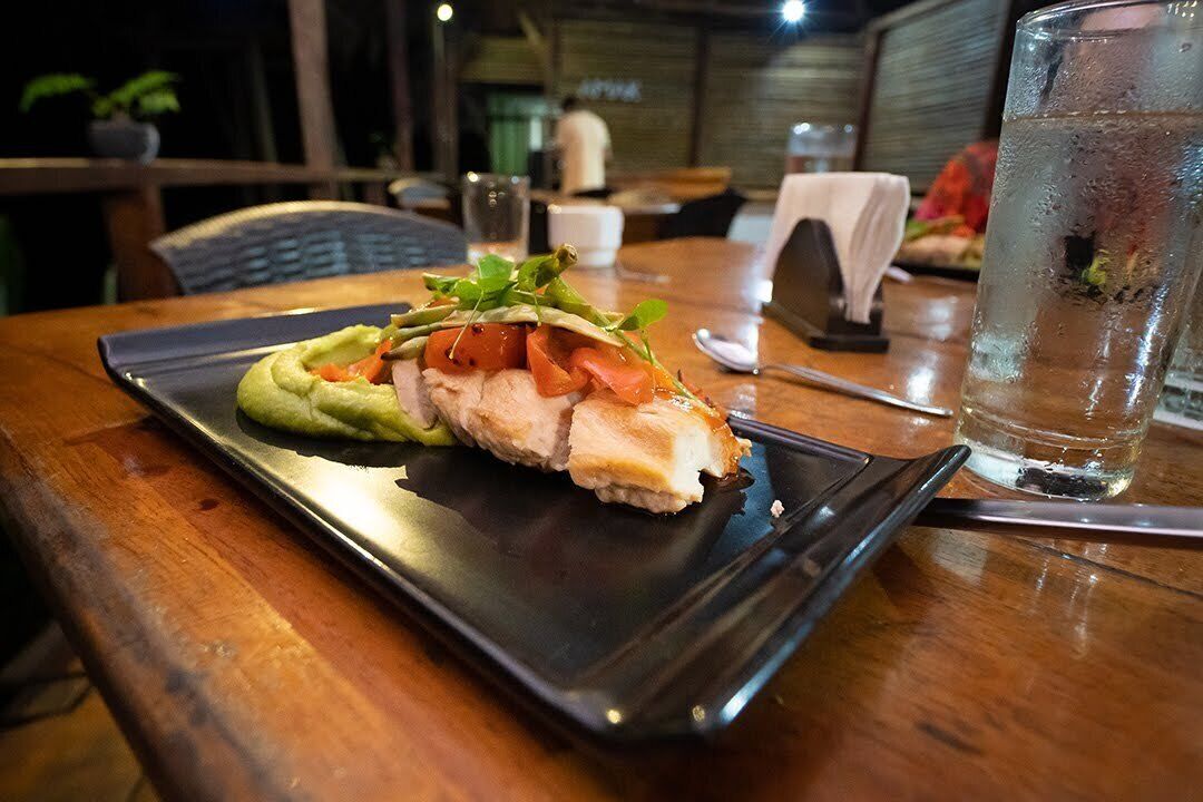 A dining table with a plate of food, a glass of water, and a spoon.
