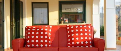 Un sofá rojo con cojines blancos de lunares en el vestíbulo de un hotel.
