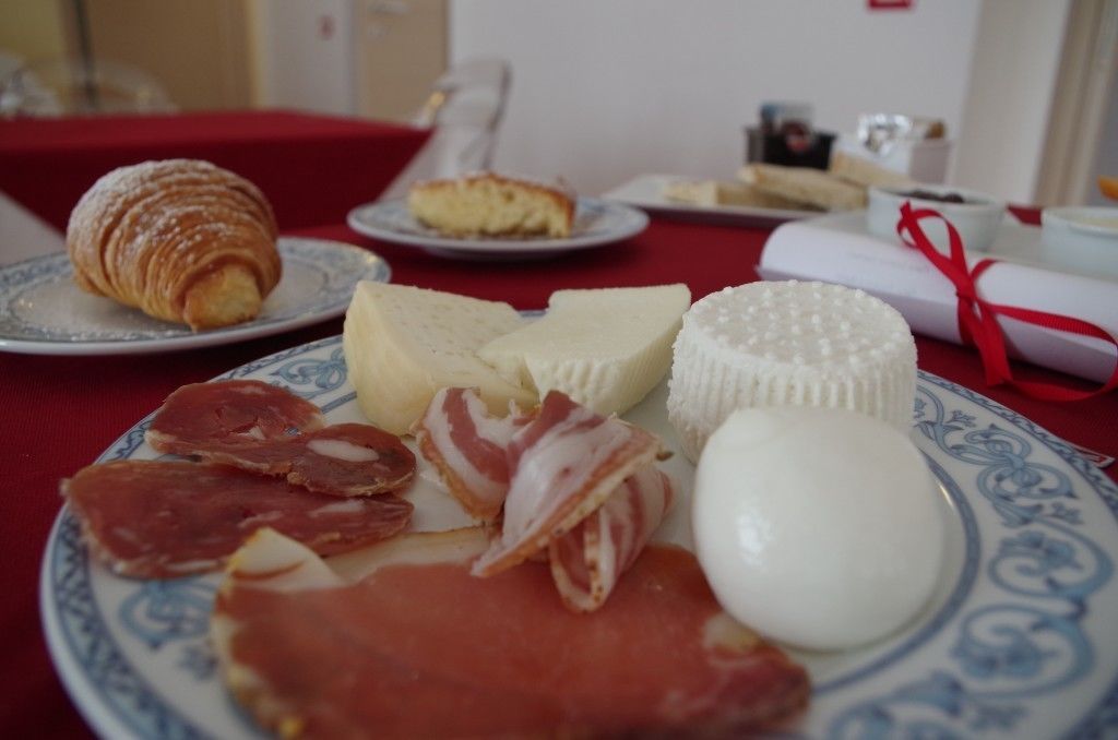 A table with various food items including a croissant, cheese, ham, and a wrapped item.