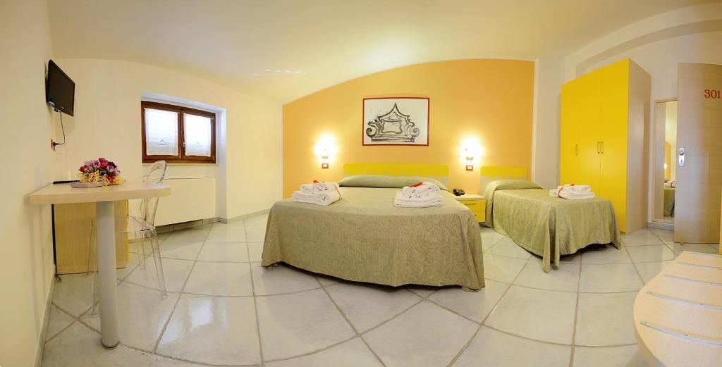 A hotel room with two beds, a desk, and a small table.
