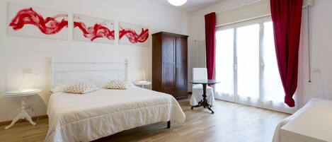 Un dormitorio moderno con una cama grande, un armario de madera, una mesita de noche y un ventanal con cortinas rojas.