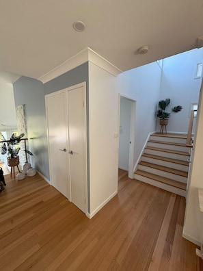 Un interior espaiós amb un paviment de fusta, una escala i una porta que dona a una altra habitació.