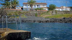 Un hôtel situé sur la côte, doté d’un mur en pierre, d’une piscine et offrant une vue sur la mer.
