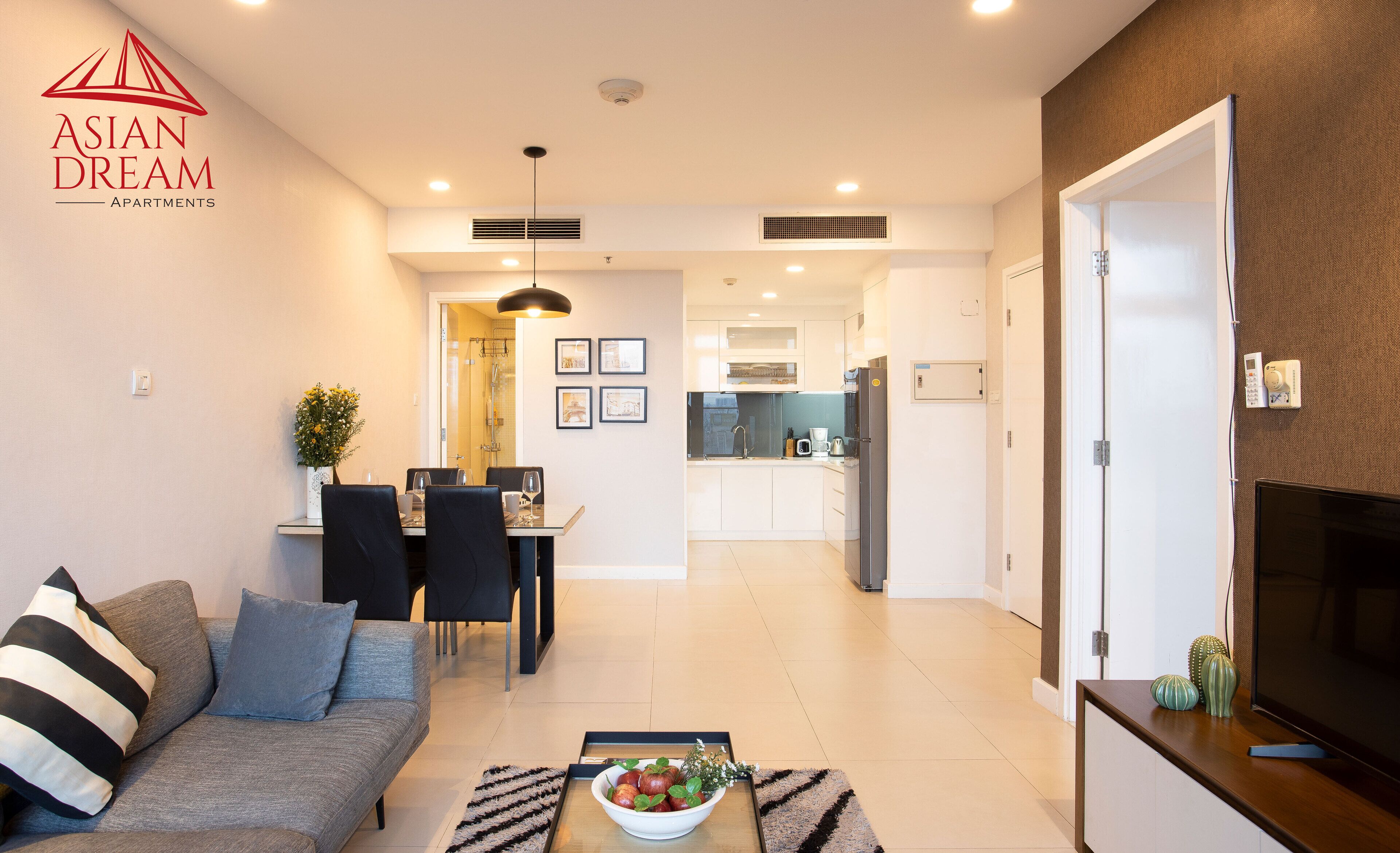 Een modern appartement met een eethoek, keuken, woonkamer en een televisie aan de rechterkant.