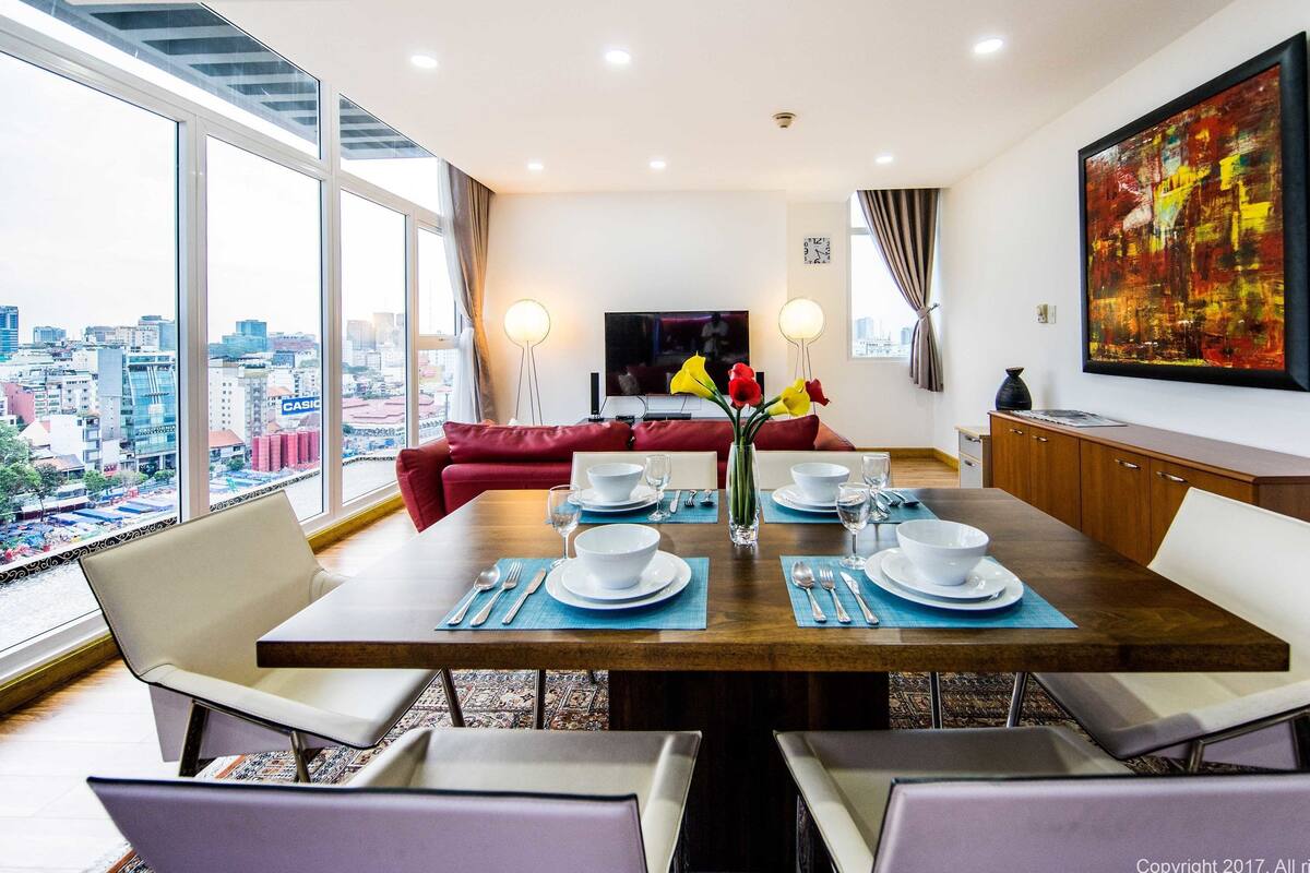 A dining area with a city view, a large painting, and a modern interior design.