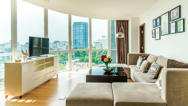 A modern living room with a large window, a flat-screen TV, a sofa, and a coffee table. - Luxury Ben Thanh TAA Apartments (Ho Chi Minh City)