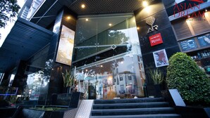 A modern building entrance with a glass facade, a sign reading "Asian Dream Apartments," and a staircase leading up to the entrance. - Luxury Ben Thanh TAA Apartments (Ho Chi Minh City)