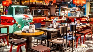 A restaurant interior with a vintage green van, red chairs, and tables. - Luxury Ben Thanh TAA Apartments (Ho Chi Minh City)