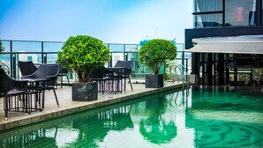A rooftop pool area with lounge chairs and potted plants, surrounded by glass railings and a view of the city skyline. - Luxury Ben Thanh TAA Apartments (Ho Chi Minh City)