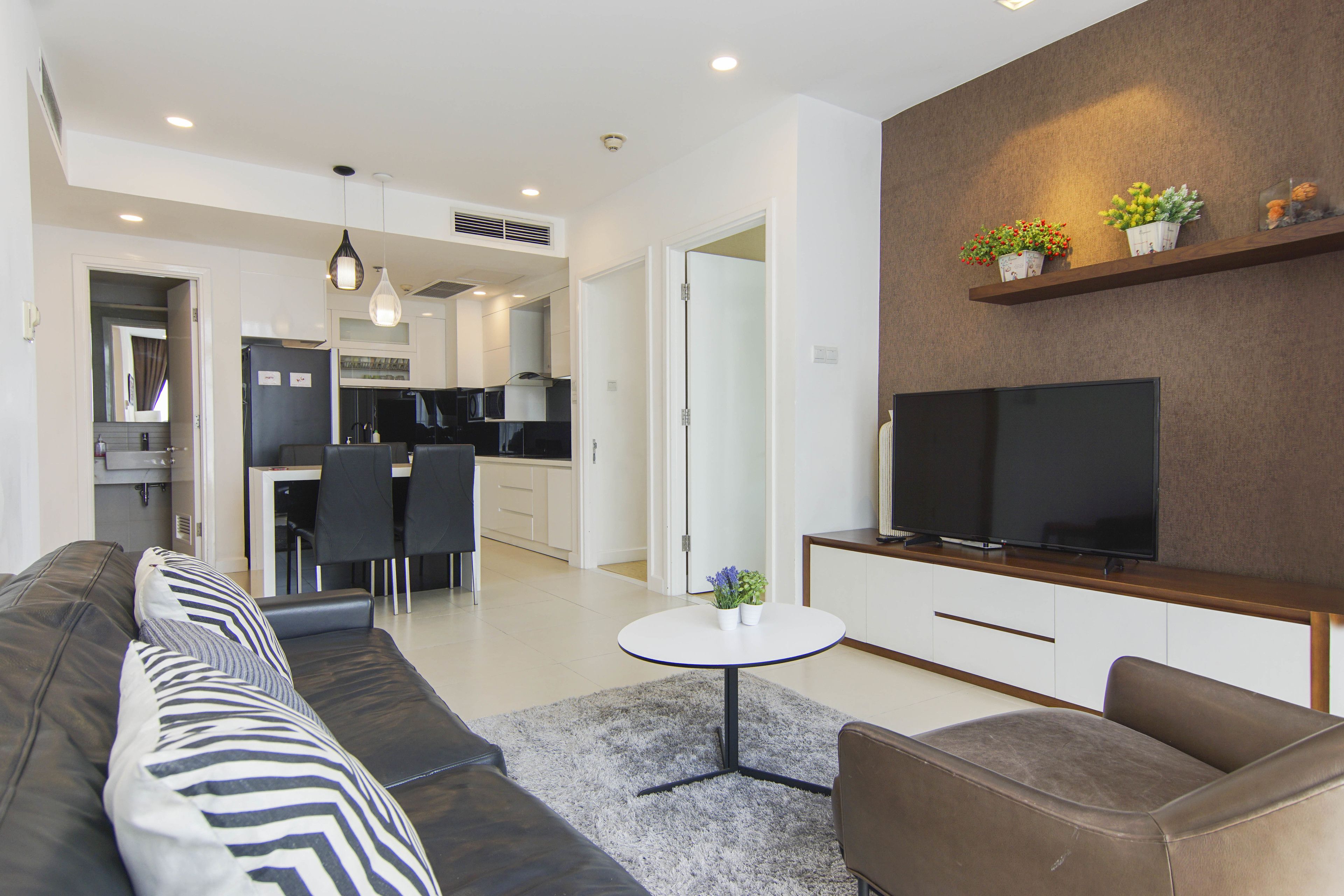 Uma sala de estar moderna com um sofá, uma mesa de centro e uma TV em um suporte.