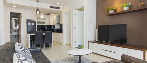 Uma sala de estar moderna com um sofá, uma mesa de centro e uma TV em um suporte.