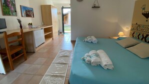 Una habitación con cama, escritorio y silla. Hay toallas sobre la cama.