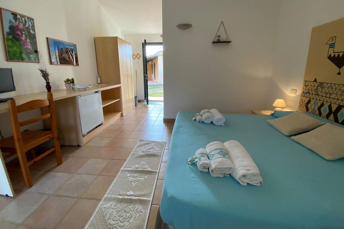 A room with a bed, a desk, and a chair. There are towels on the bed.