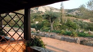 Un espacio al aire libre techado con vista a un paisaje montañoso, que incluye árboles y un edificio a lo lejos.